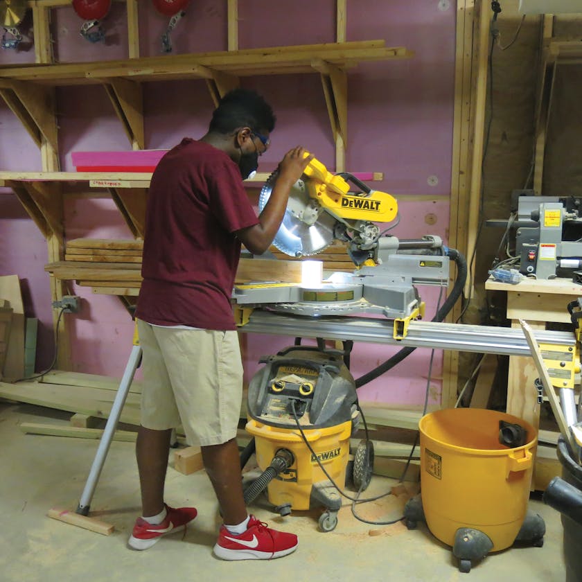 Tiny WPA Building Hero Terrell Smith cutting wood for a mobile playground