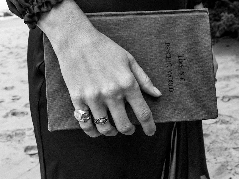An antique book held by a hand wearing jewelry