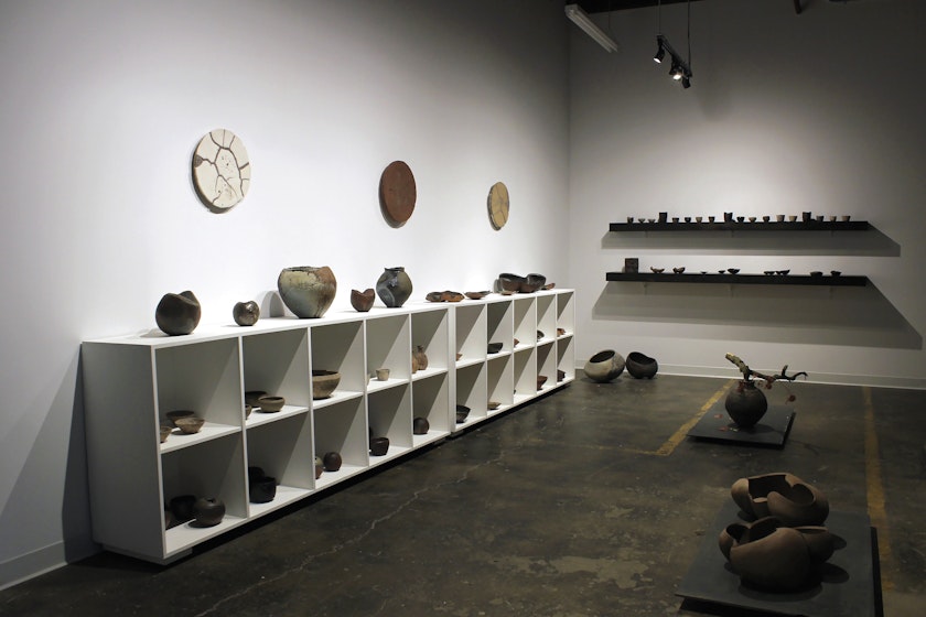 Minimal dimmly lit ceramics gallery with various vessels on display
