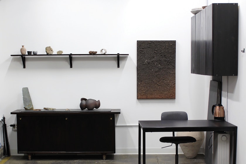 Minimal office space with black furniture and various ceramic pieces on display