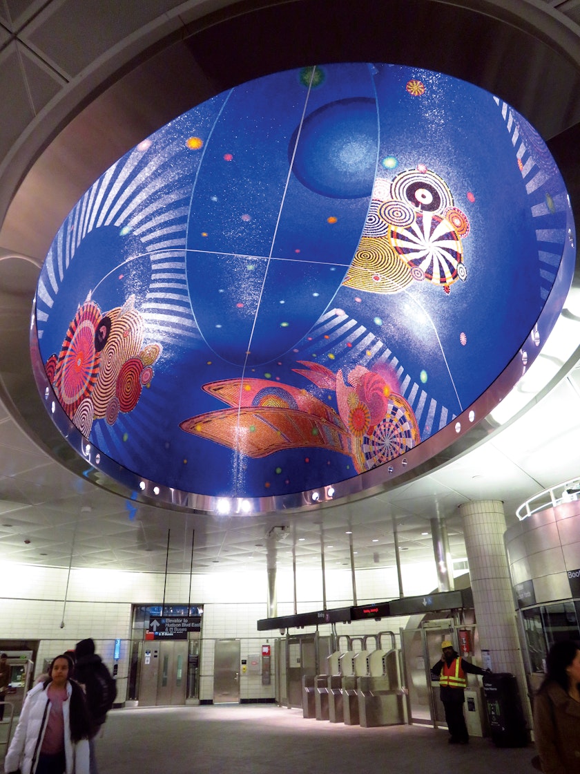 Transit station ceiling art featuring crocheted mandala designs on a blue background