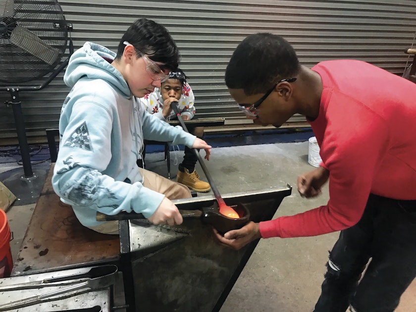 Three young people working together on a blown glass project