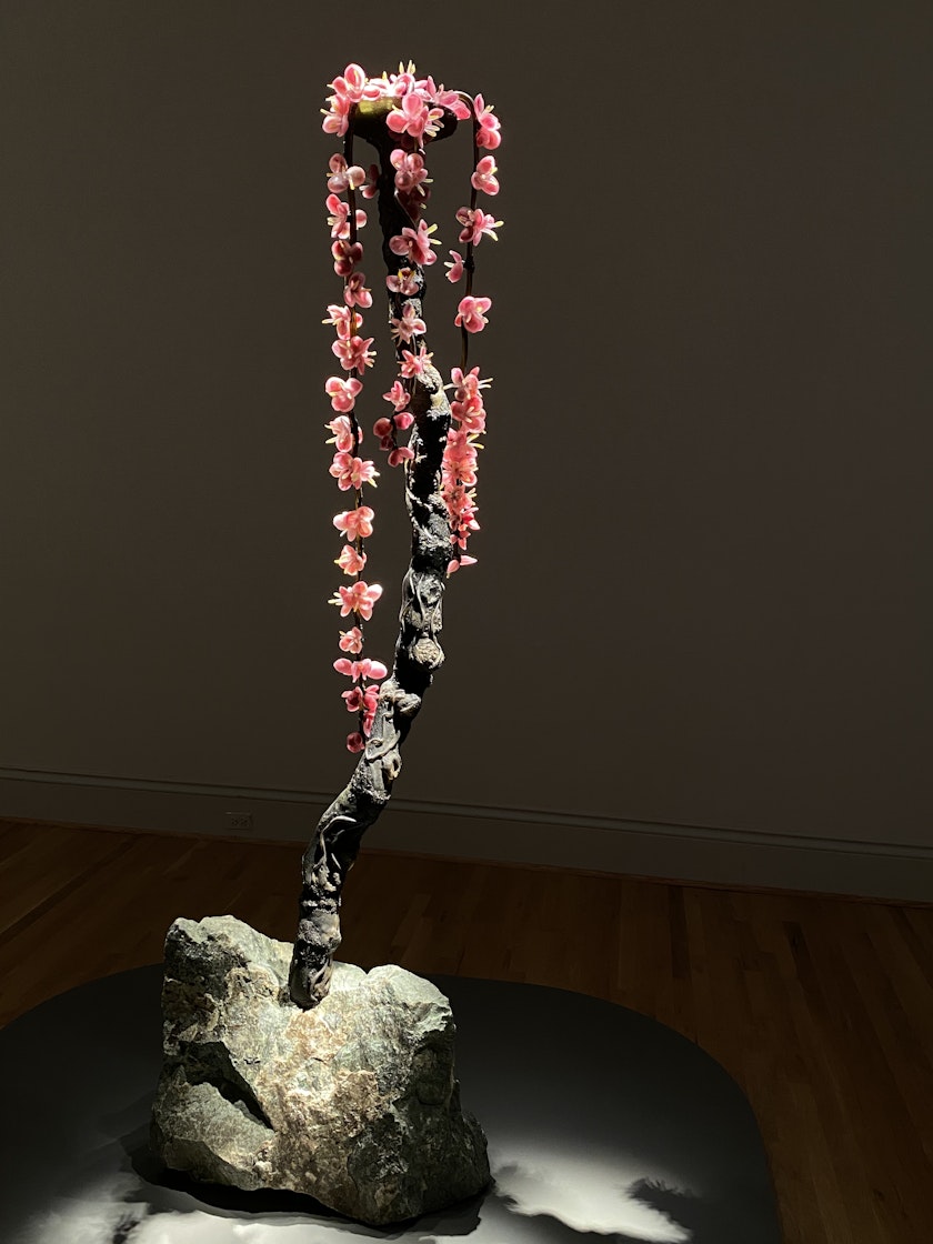 Blown glass cheryy blossom branch extending from a boulder