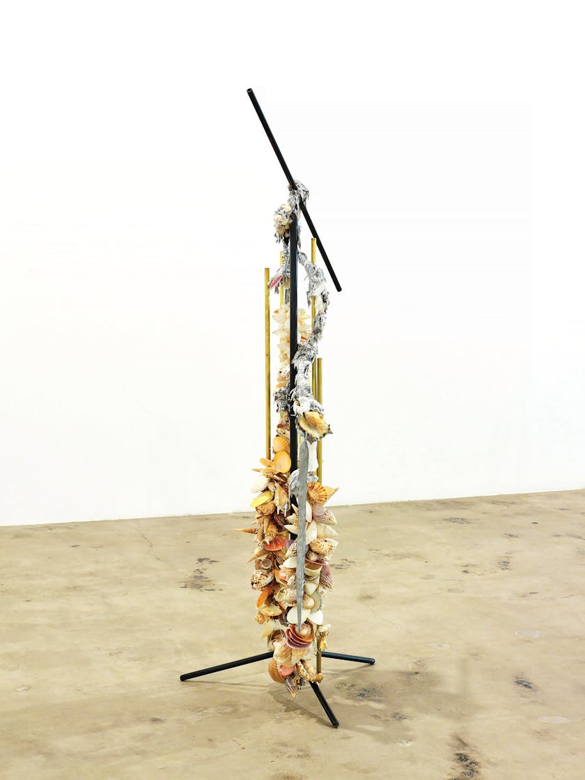 Sculpture made from mic stand laden with seashells and other miscellaneous debris