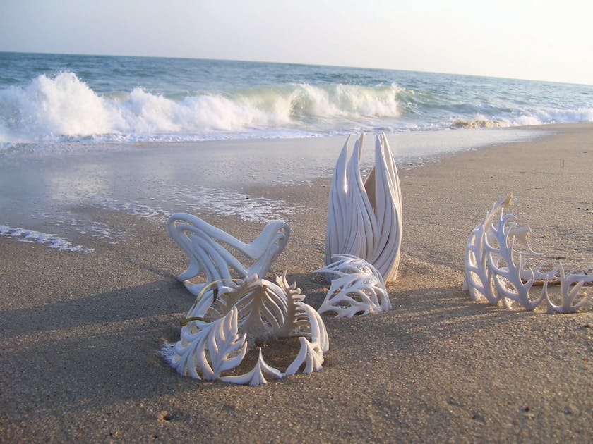 Beach with half buried porcelain sculptures made to look like whale bones and other ocean skeletons