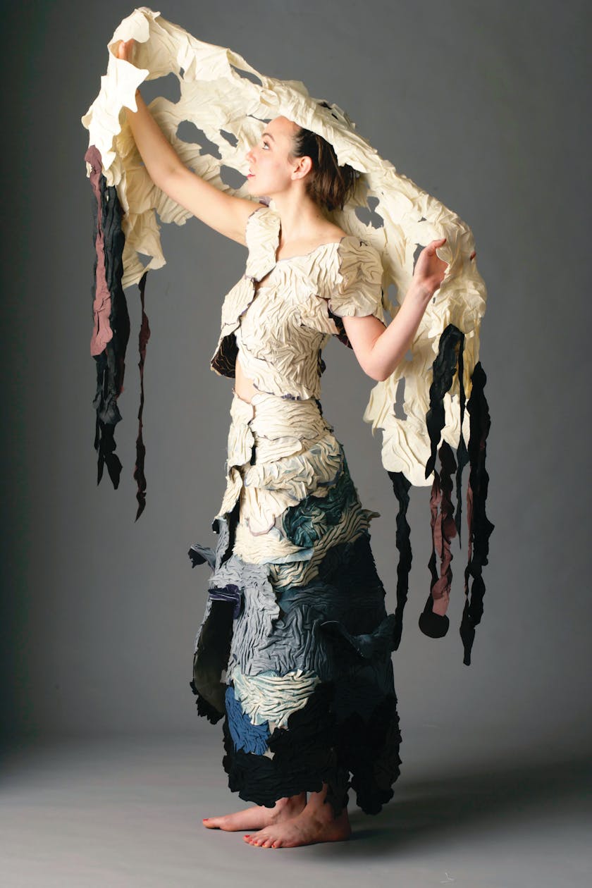 Woman in textured dress inspirted by an ocean oil spill holding up a matching shawl