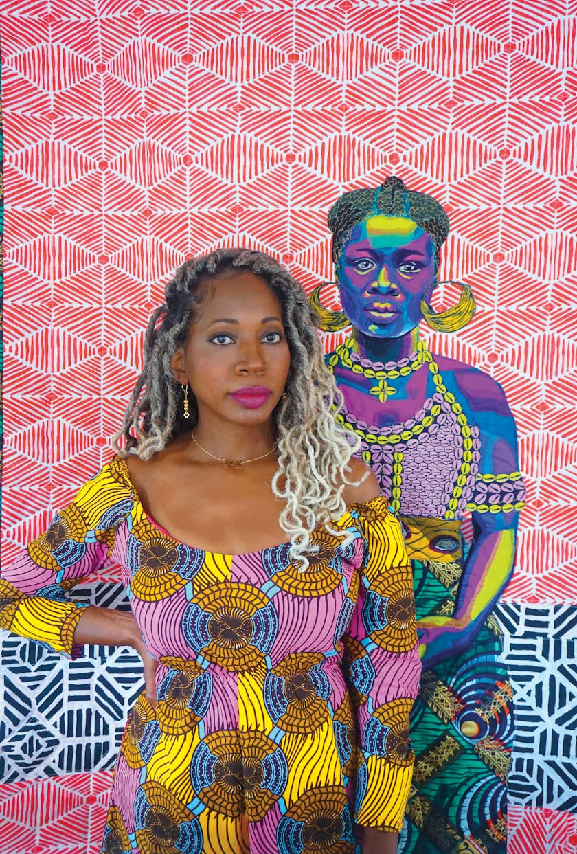 woman in colorful patterned clothes standing in front of a colorful patterned quilt featuring a portrait of a woman