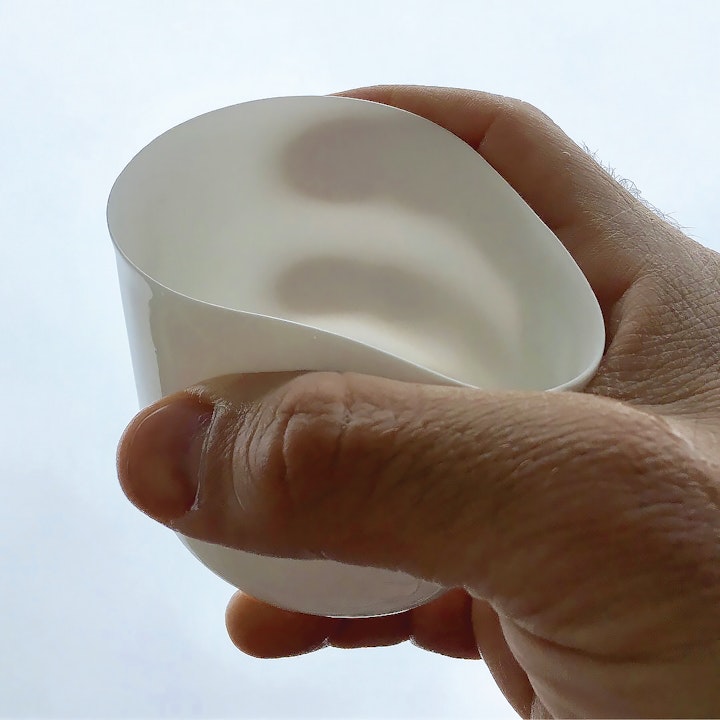 hand holding a small white bone china cup