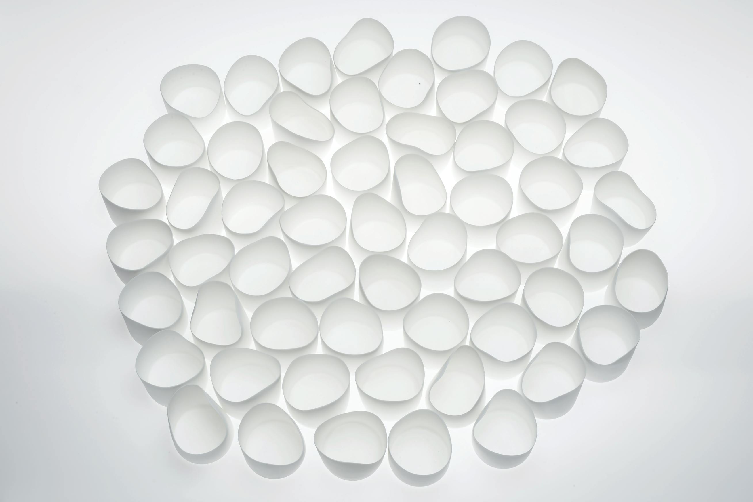 grouping of small white irregularly shaped bone china cups on a white surface