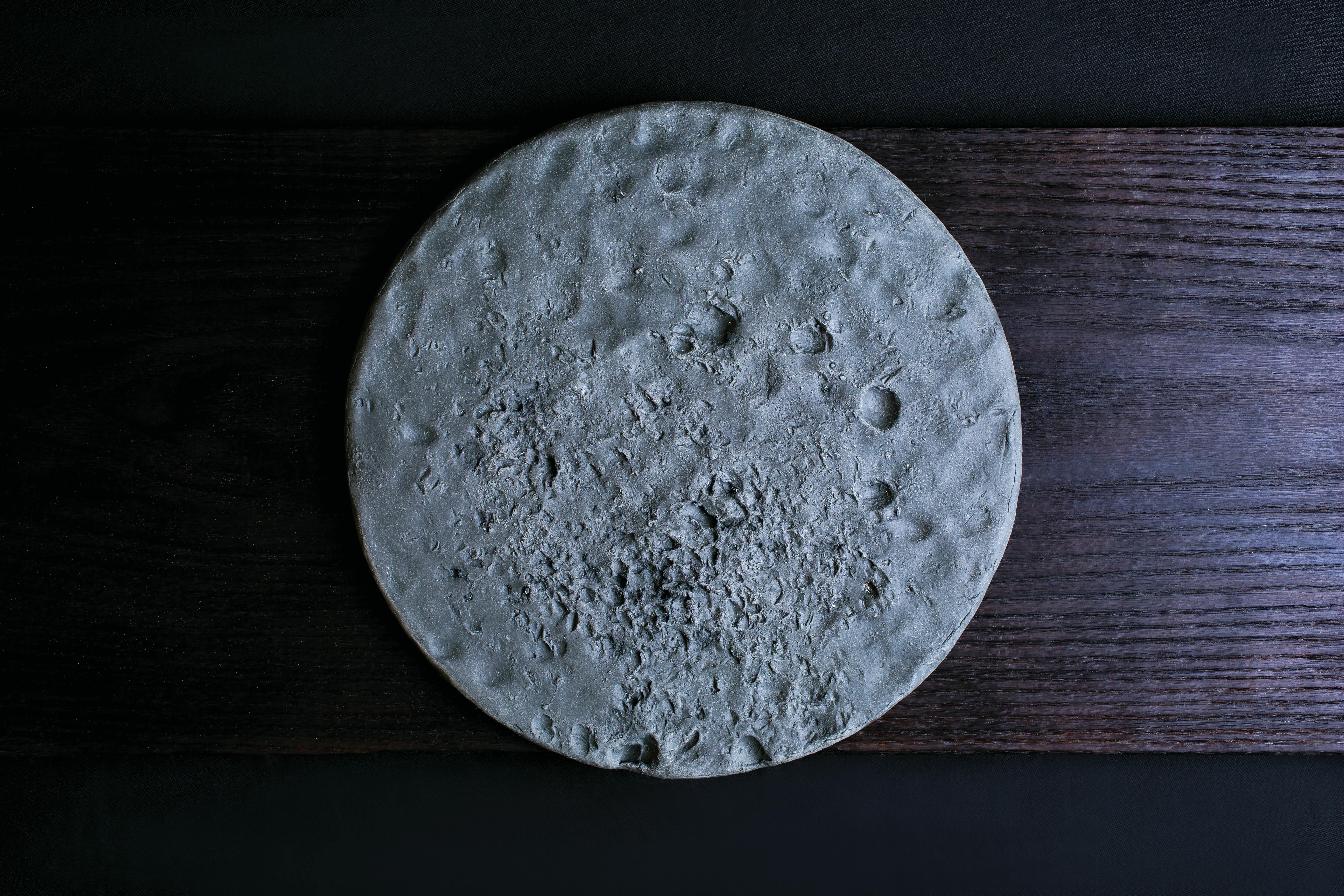 Gray round pocked ceramic plate on wood planks