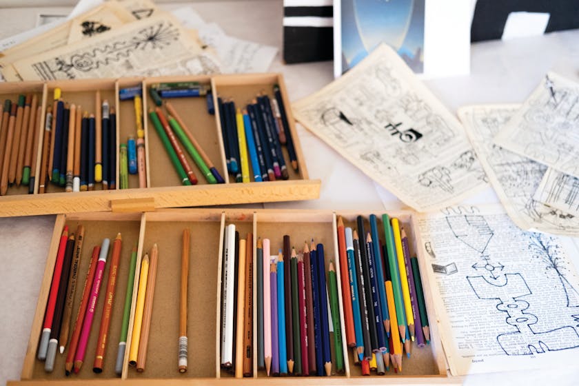pencils in trays next to drawings on book pages