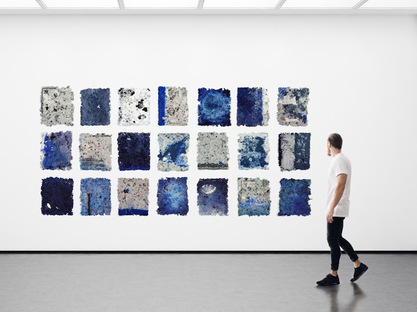 wall of an exhibition space with grid of rice paper sheets made using human hair and blue color