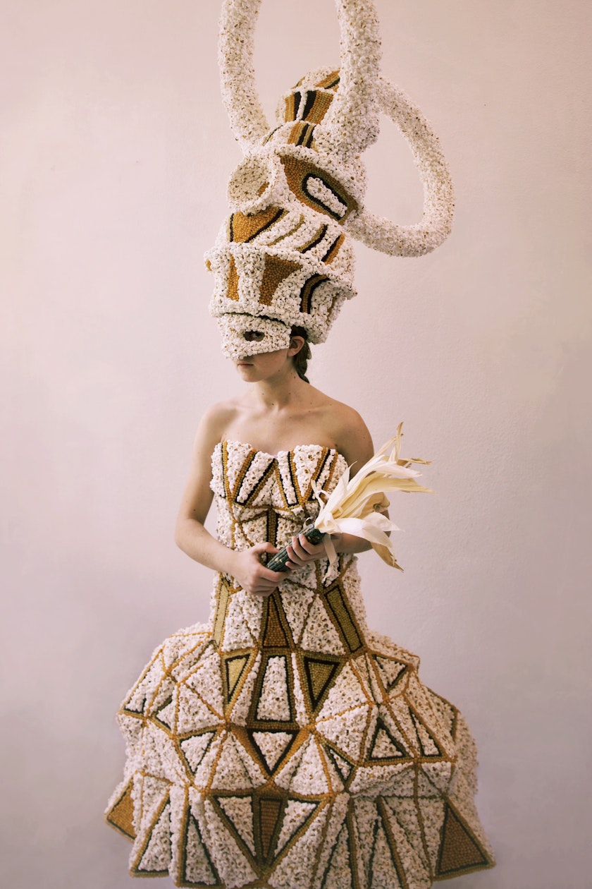 model wearing sculptural hat and dress made from popped corn and corn kernels