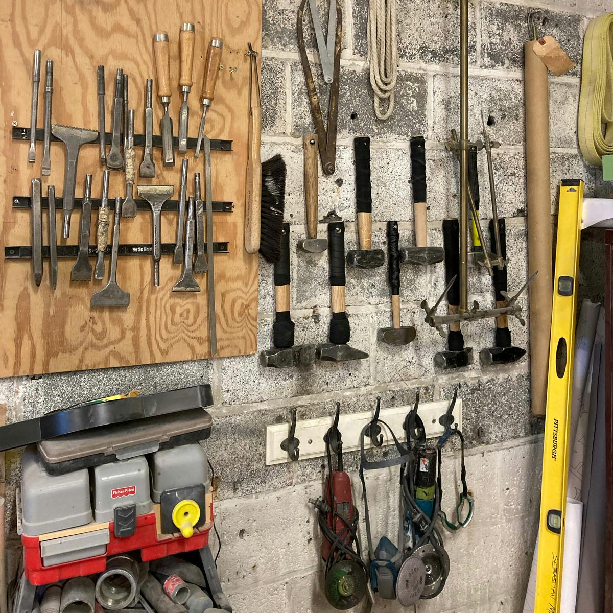 a wall in a stone carvers studio with an array of hammers, chisels, and grinders