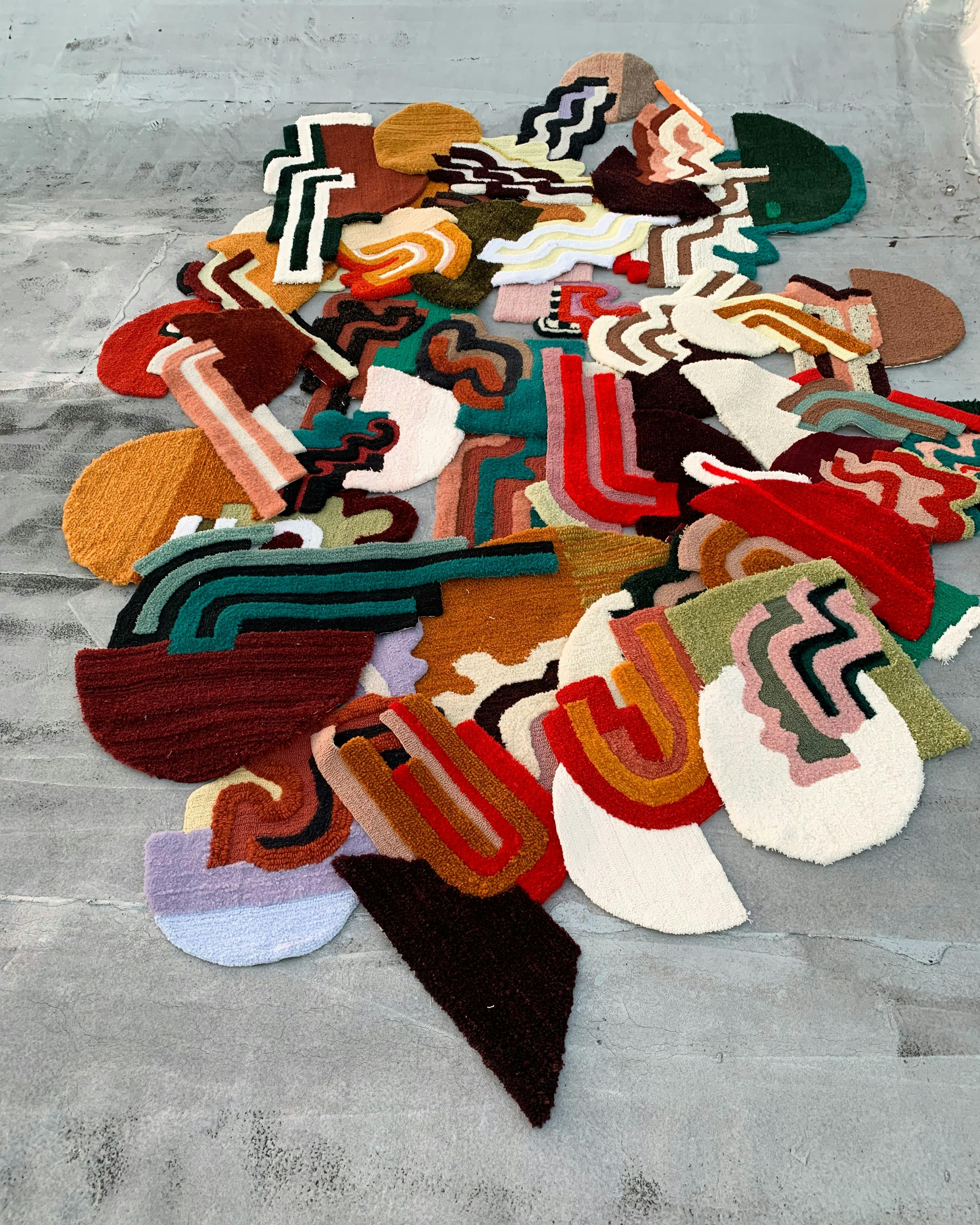 assorted colorful irregularly shaped hand tufted rugs on a gray floor