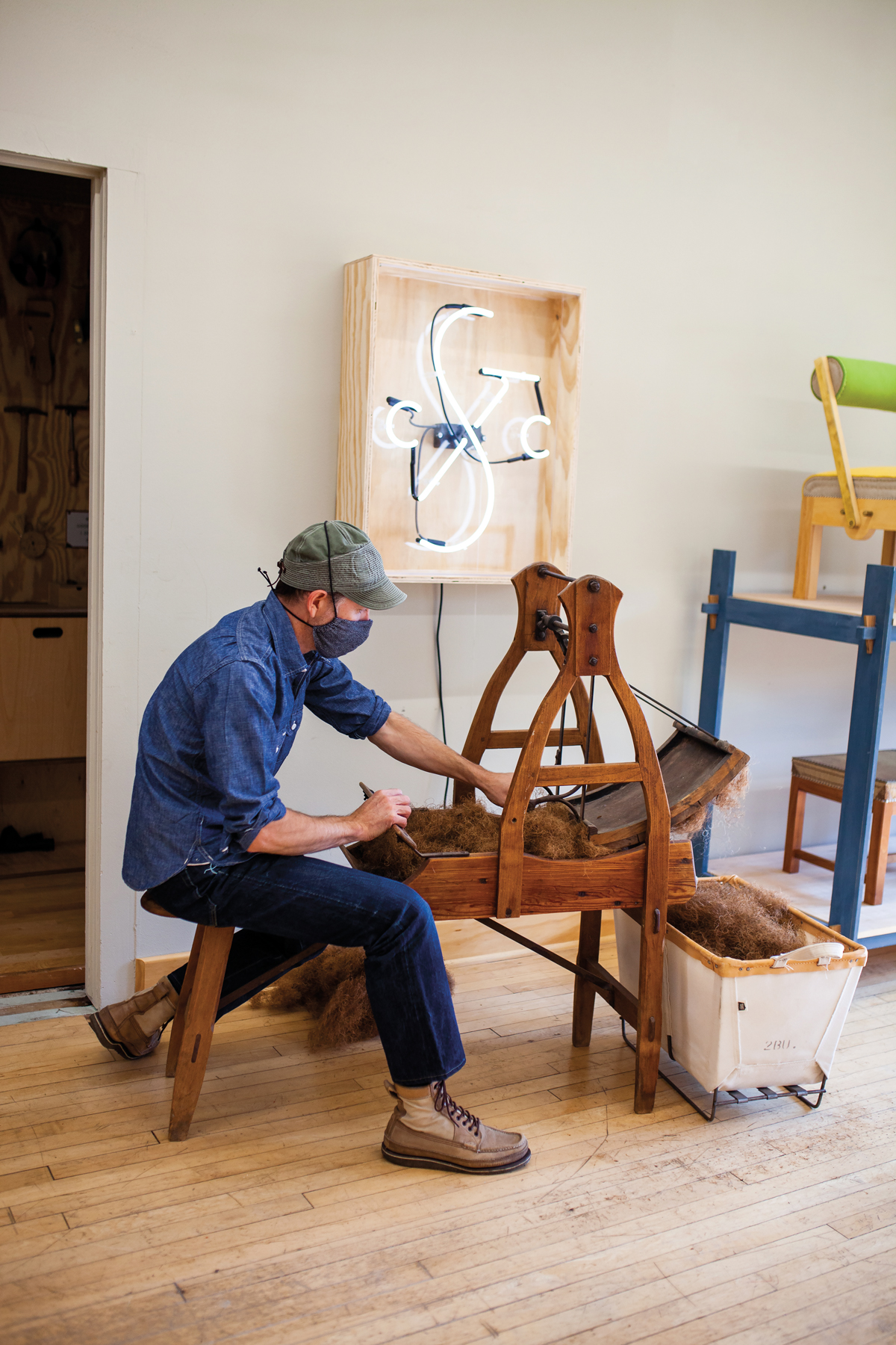 traditional furniture artist using an antique device to create coarse natural fiber for stuffing furniture