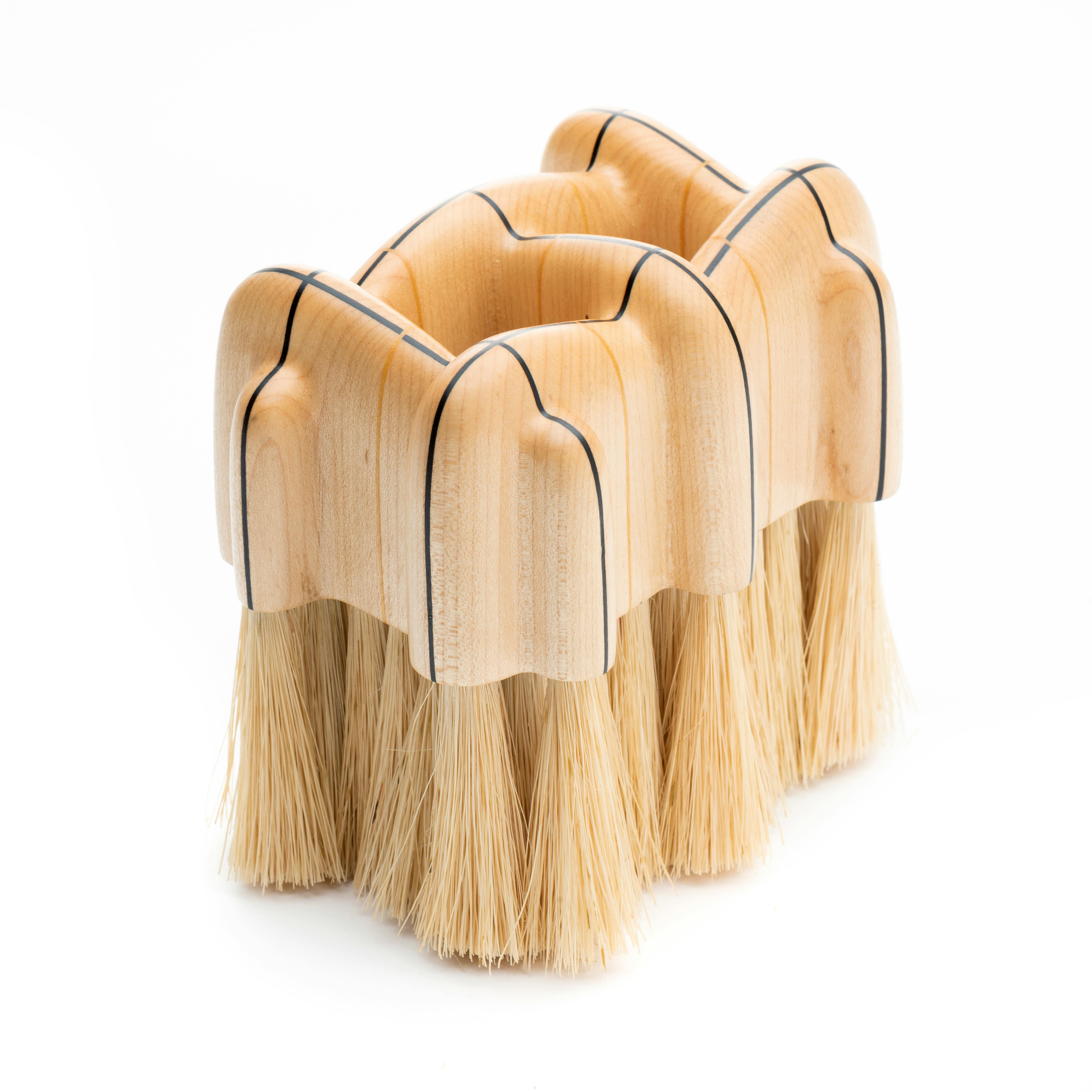 wooden brush with natural fibers and a handle that you pinch your fingers into
