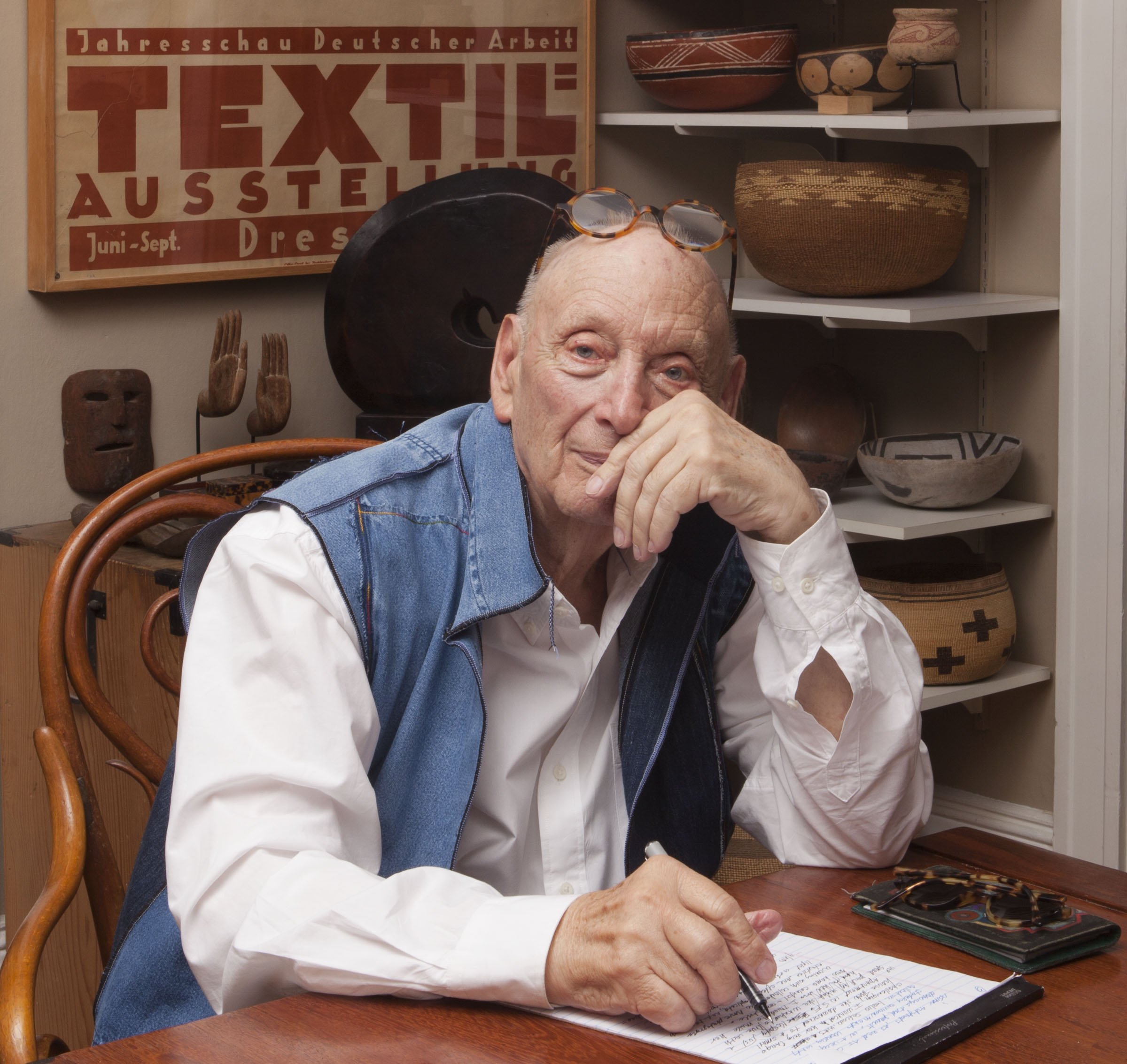 portrait of ted cohen with a white shirt and blue vest posing seated at a desk with a pad of paper
