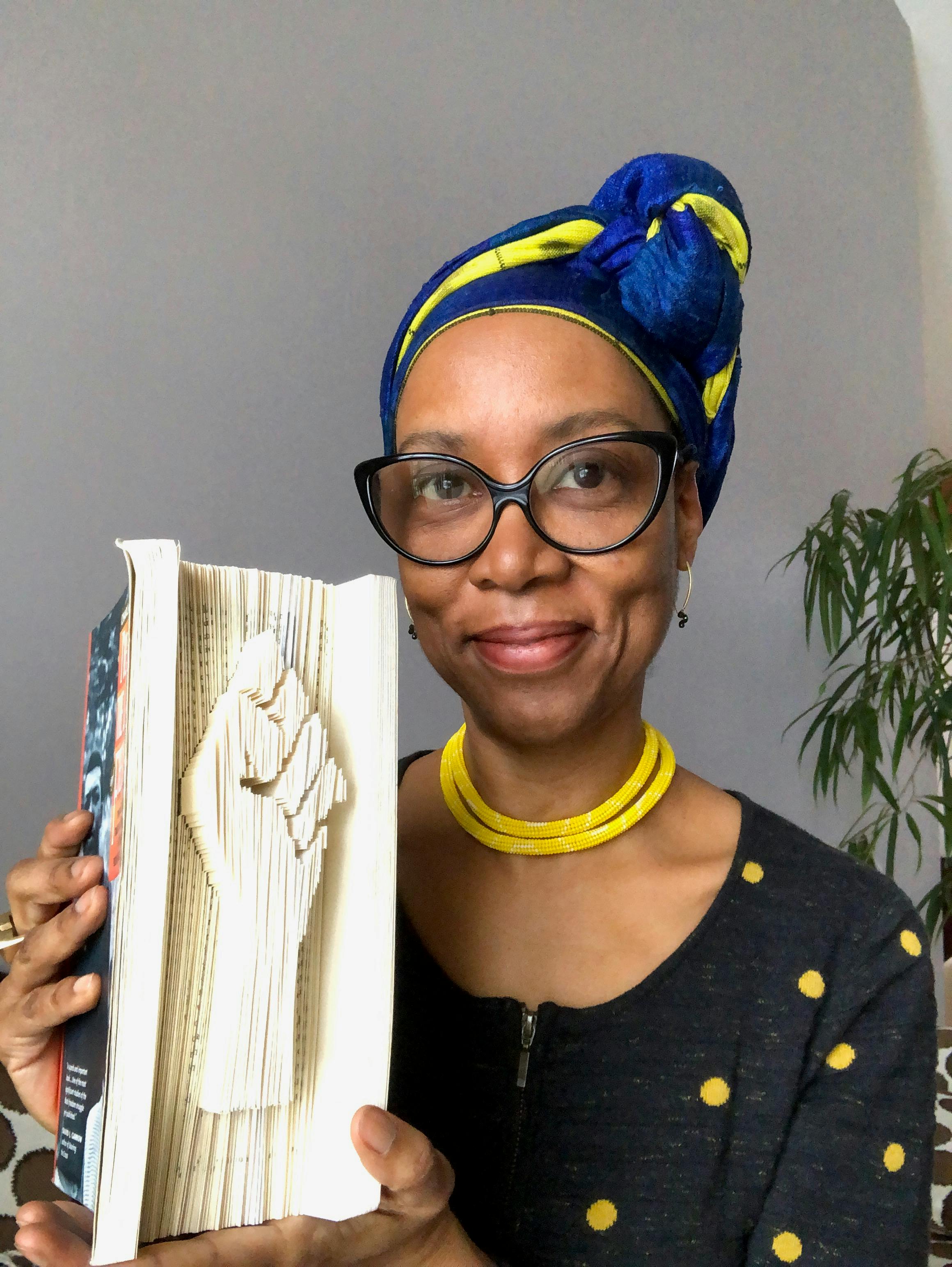 portrait of sonya clark holding book with solidarity fist symbol carved into the ends of the pages