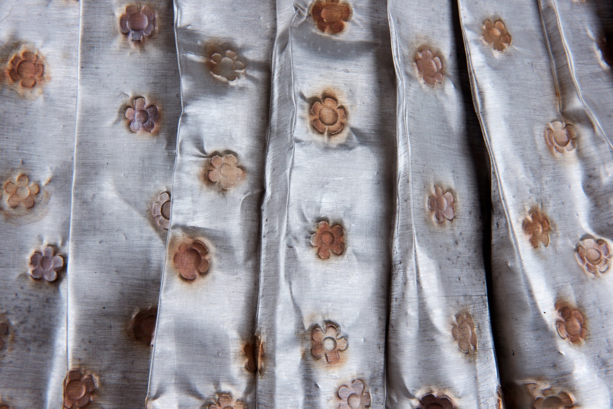 detail of sculpture of an apron with floral print made from metal