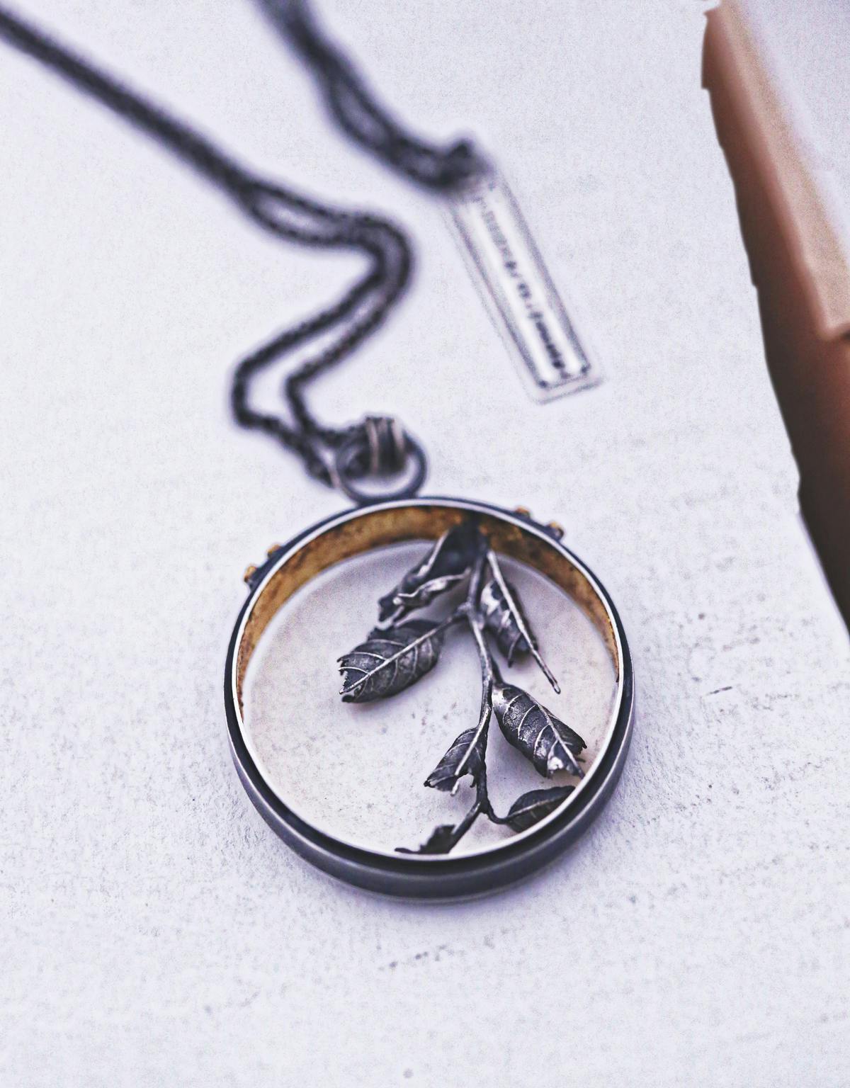 metal ring on necklace with leaf design in the middle of the ring