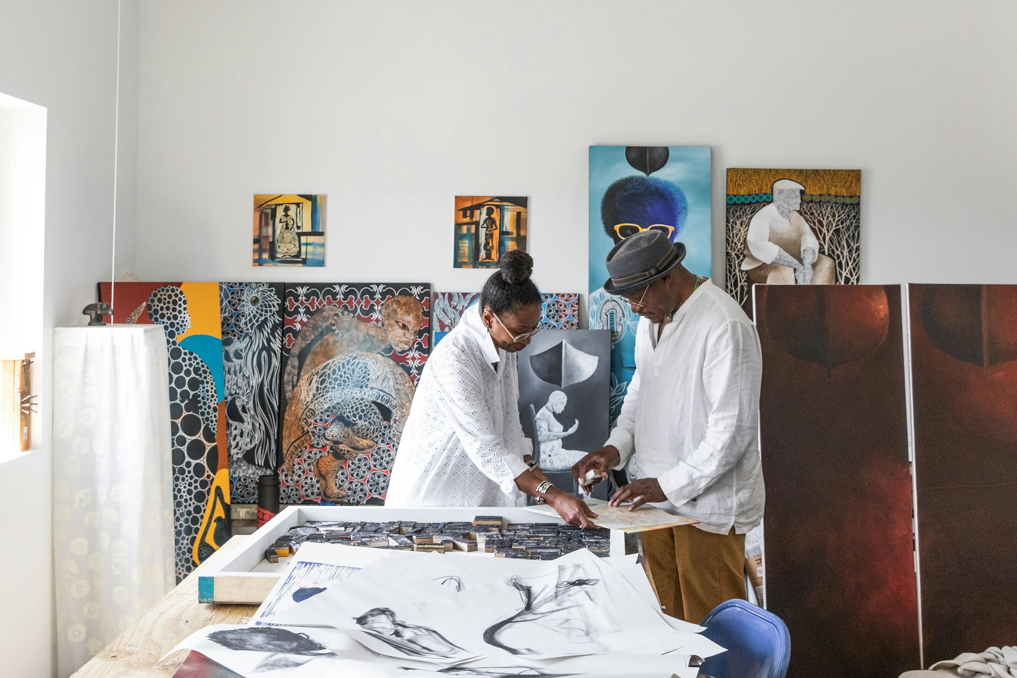 man and woman working together in studio surrounded by paintings