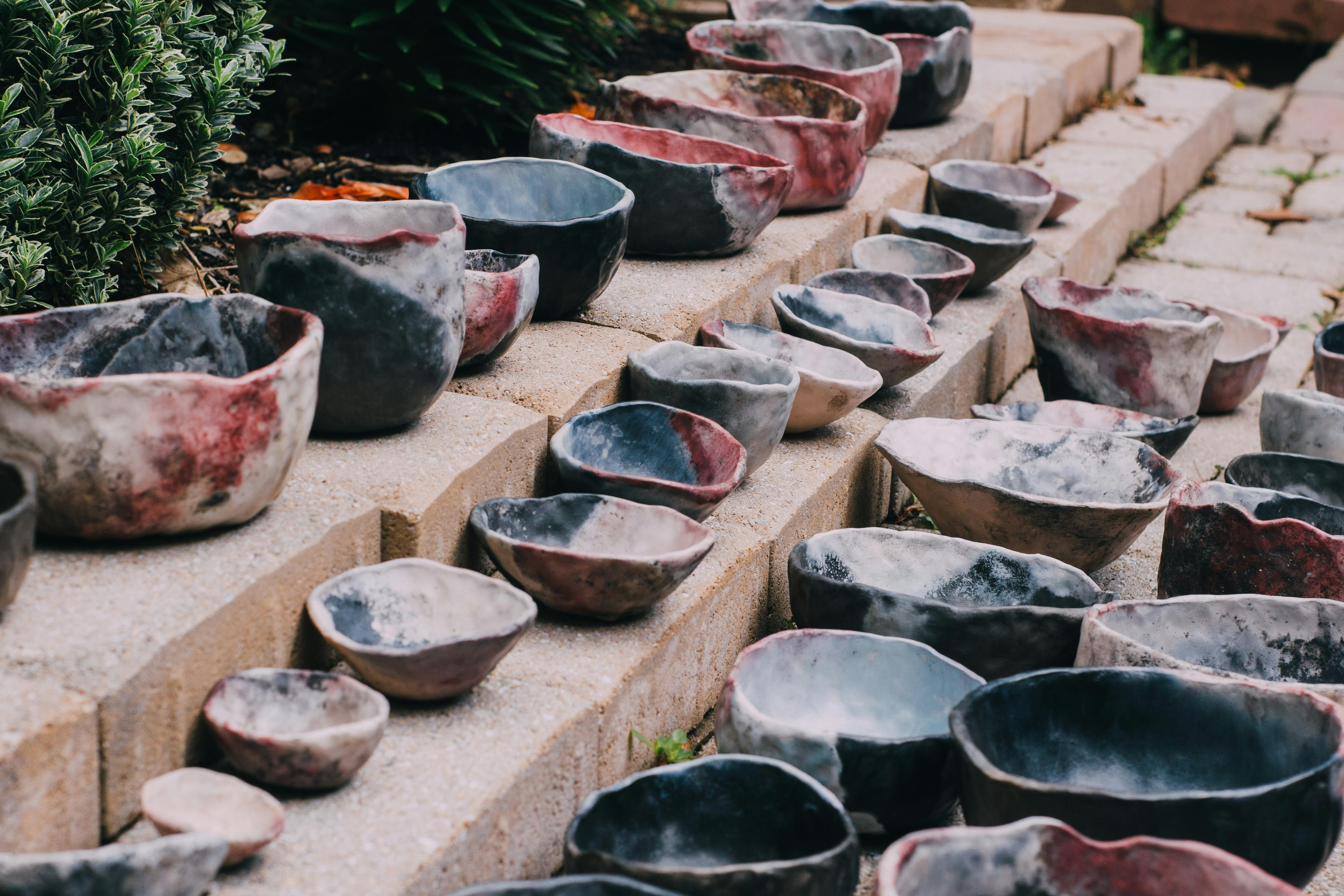 various handshaped earthtoned bowls arranged on brick steps
