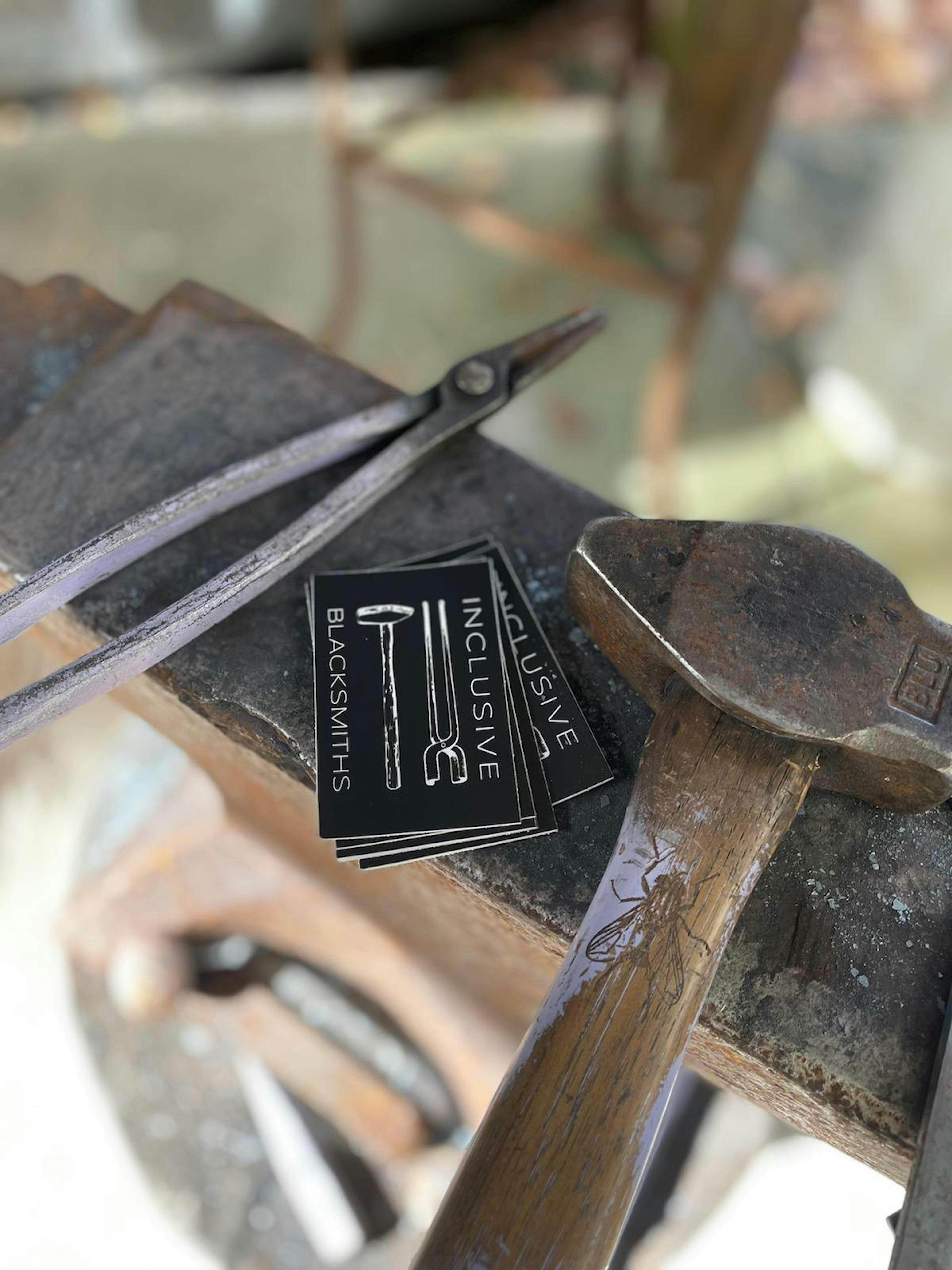 blacksmithing tools resting on an anvil beside a stack of business cards
