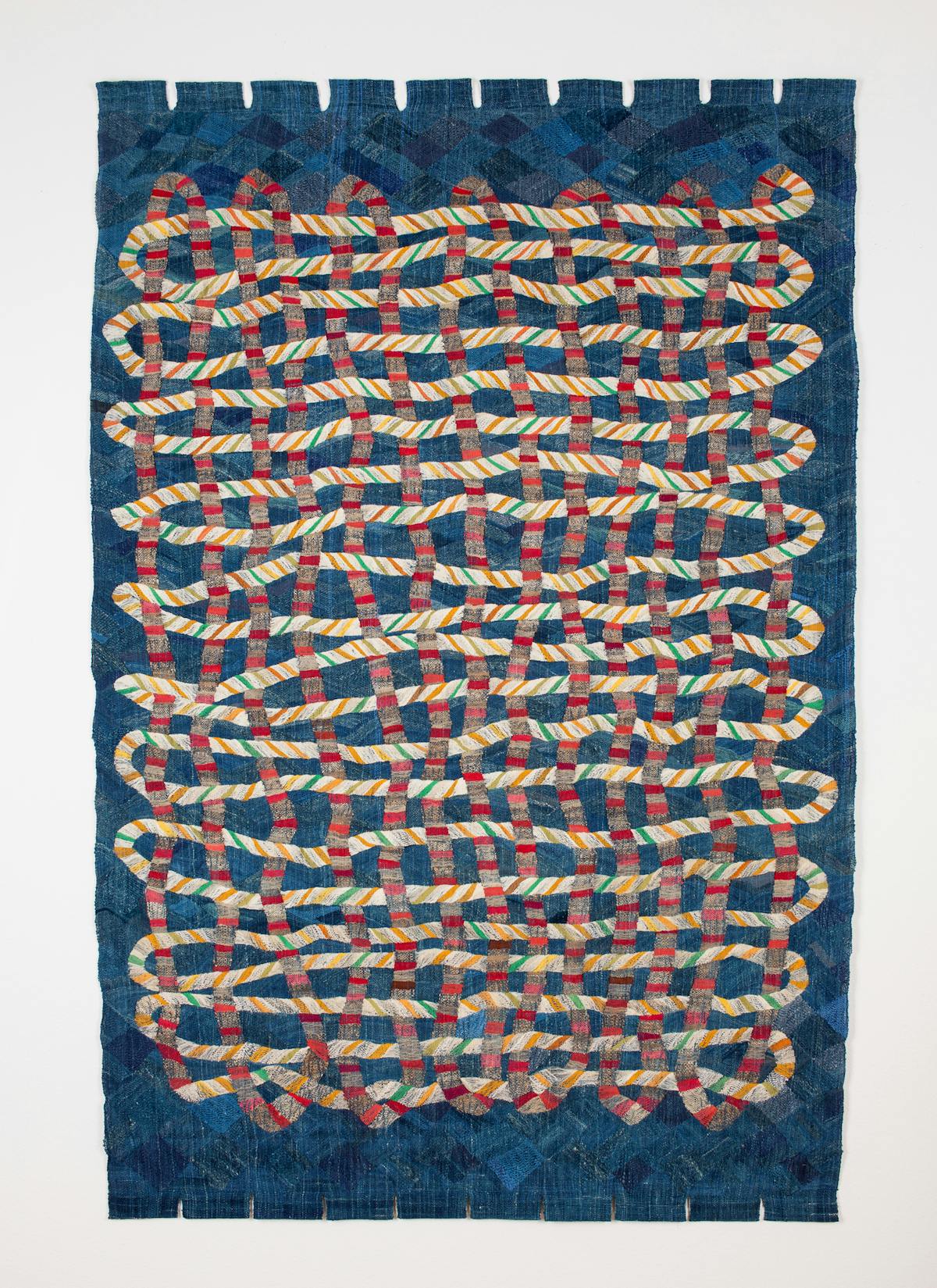 blue tapestry with image of a rope weaving in red and cream colors