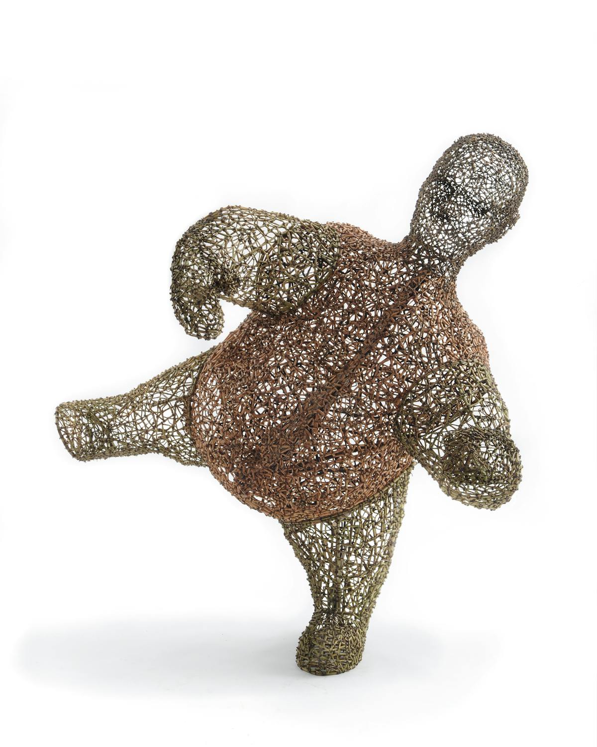 sculpture of a short squat man balancing on one leg made from woven natural material in a basket like fashion