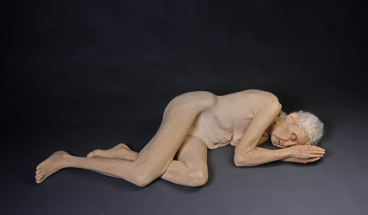 ceramic sculpture of a nude woman lying on her side on the floor