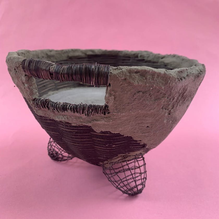 Woven sculptural basket with cement and pink background