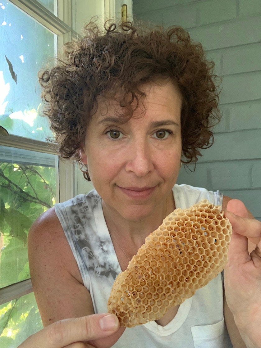 Woman next to a window holding up a piece of honeycomb