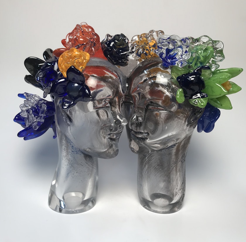 Two glass heads adorned with colorful glass flowers
