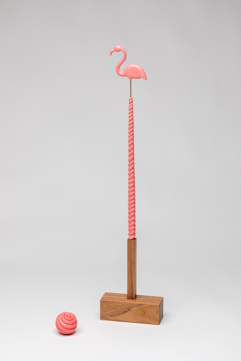 Wooden mallet with pink swirling handle topped with pink flamingo beside pink swirled ball