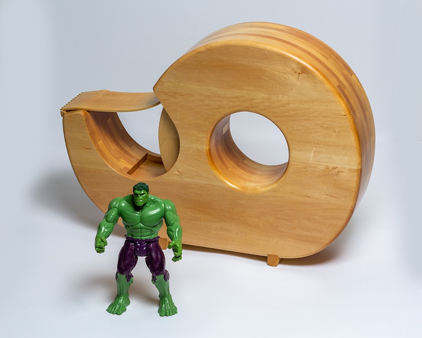 Wooden sculpture of a tape dispenser beside figurine of The Hulk