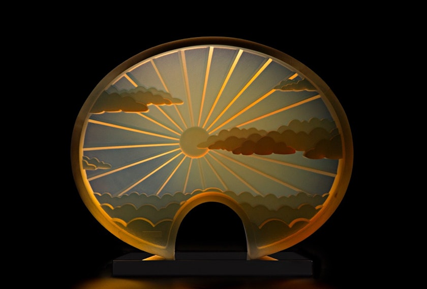 glass object depicting a sun shining through clouds and refracting subtle warm hues