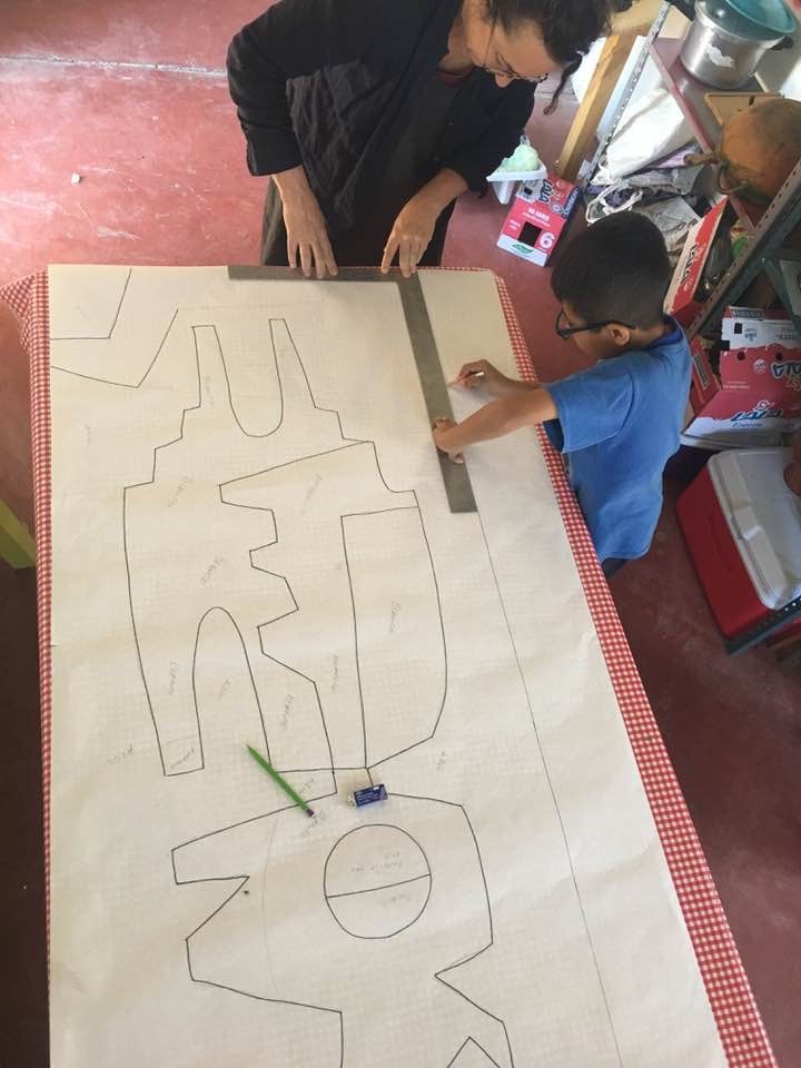 artist working on a large symbolist drawing with a young boy