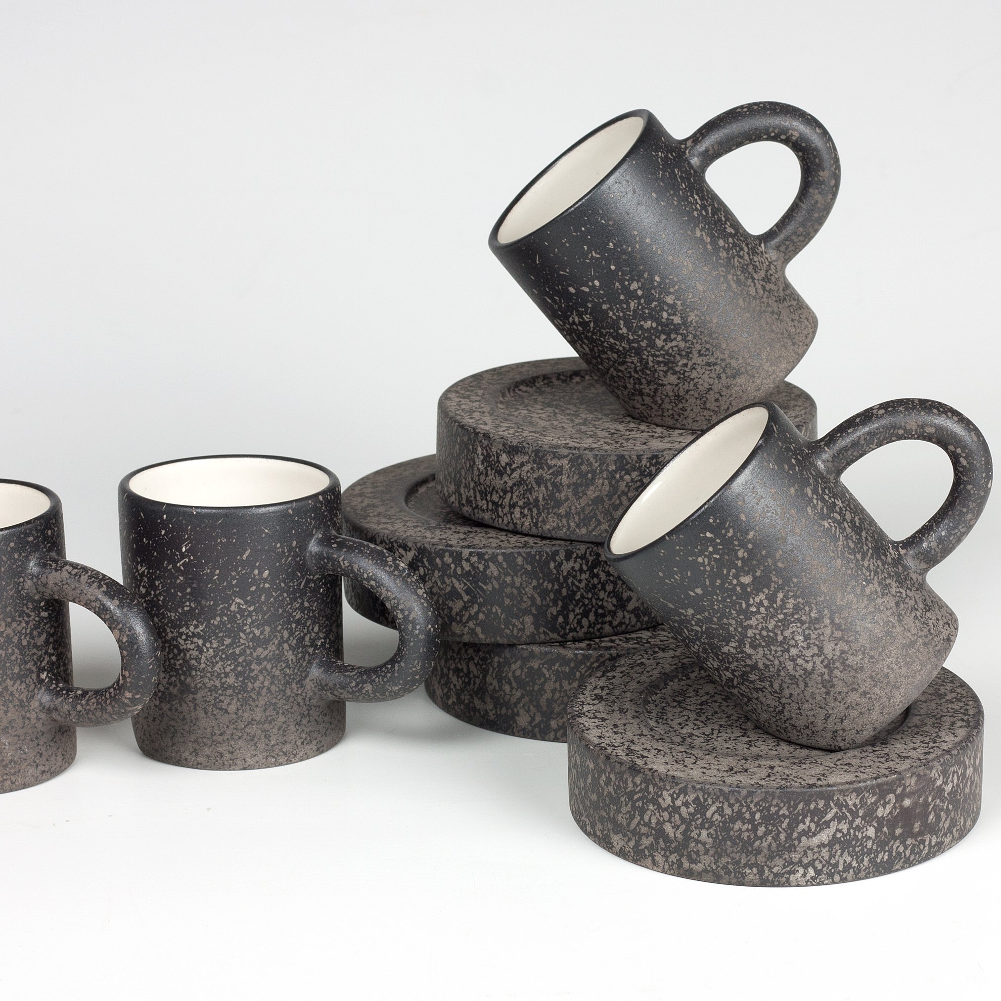 assortment of dark gray porcelain mugs on saucers