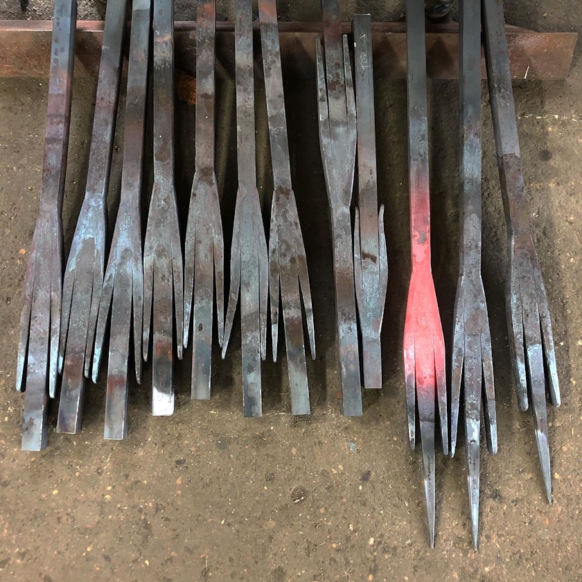 set of rough iron rods with sharp pronged ends one of them is glowing from just having been heated