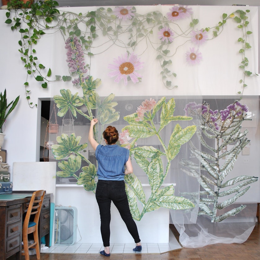artist working with large-scale prints of prairie plants on fabric in a studio space