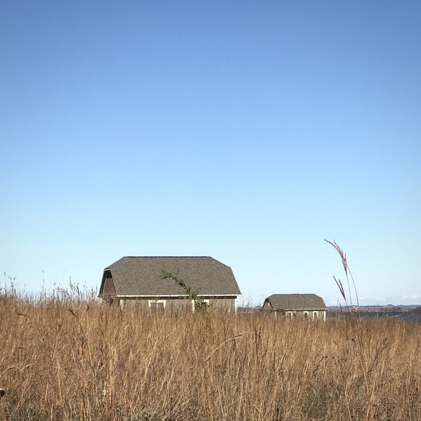 barn-like buildings of a homestead among prairie fields