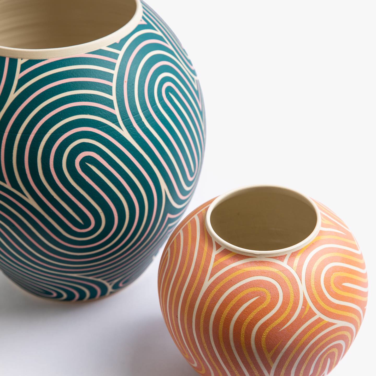 two ceramic vessels with overlapping maze-like pattern, one blue and one orange