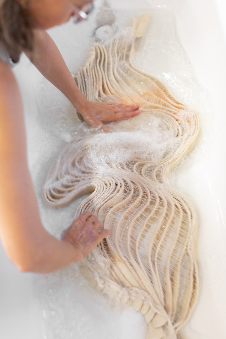 artist shaping a felt sculpture in a bath of soapy water