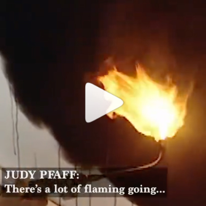 screenshot of a video of hanging fabric being burned with a torch