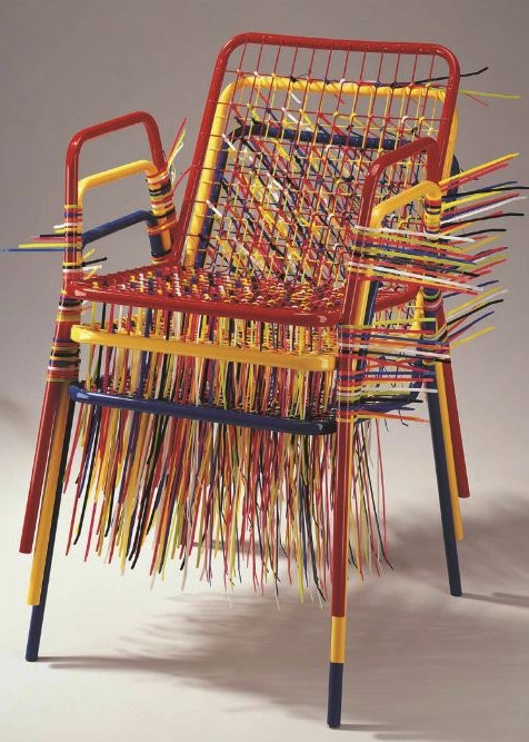 artistic chair that appears to be three red yellow and blue steel chairs stacked on one another and held together by red yellow and blue zip ties