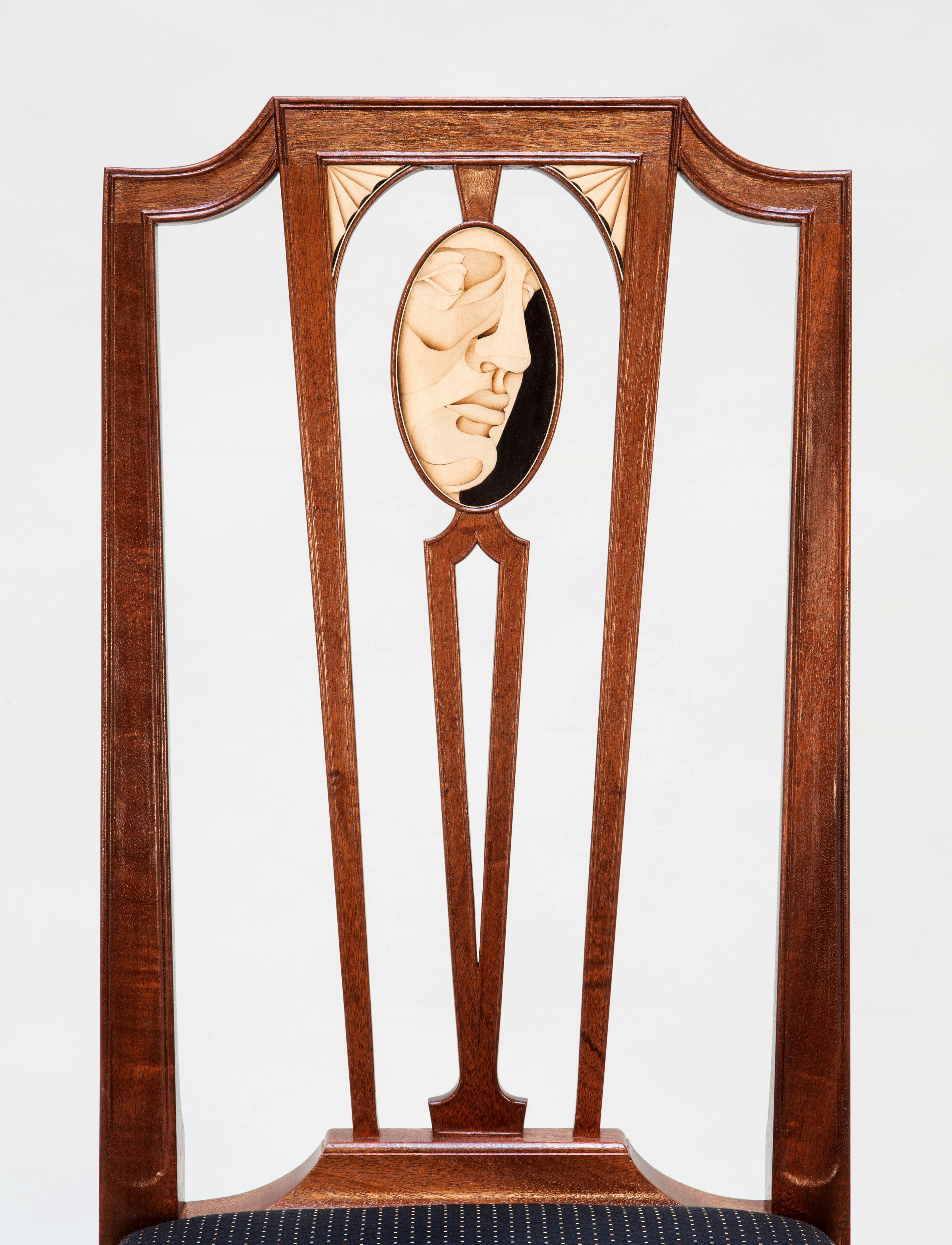 brown wooden chair back with the design of a face inlaid in an oval