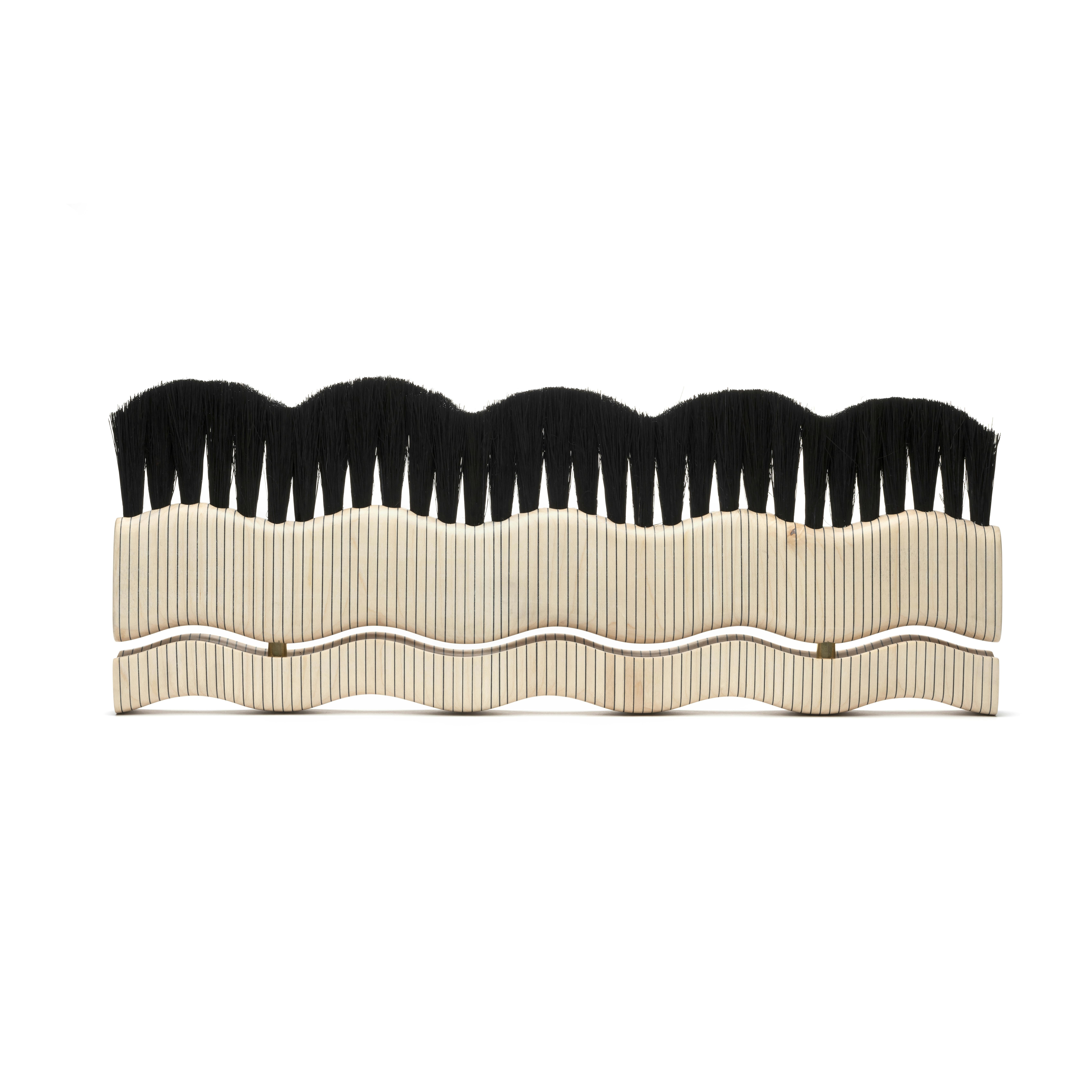 handmade brush with wide wavy shape with black bristles and wood handle