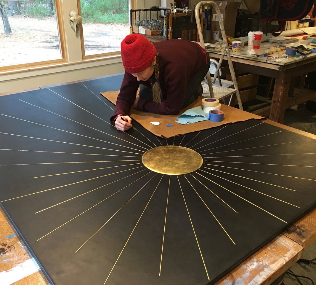 artist at work in studio on a leather panel