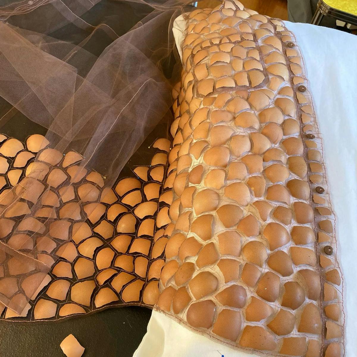 instagram screenshot of a garment being made from broken eggshells being sewn together between layers of tulle